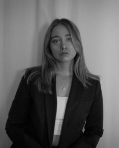 black and white image of a girl wearing a black blazer on a white background